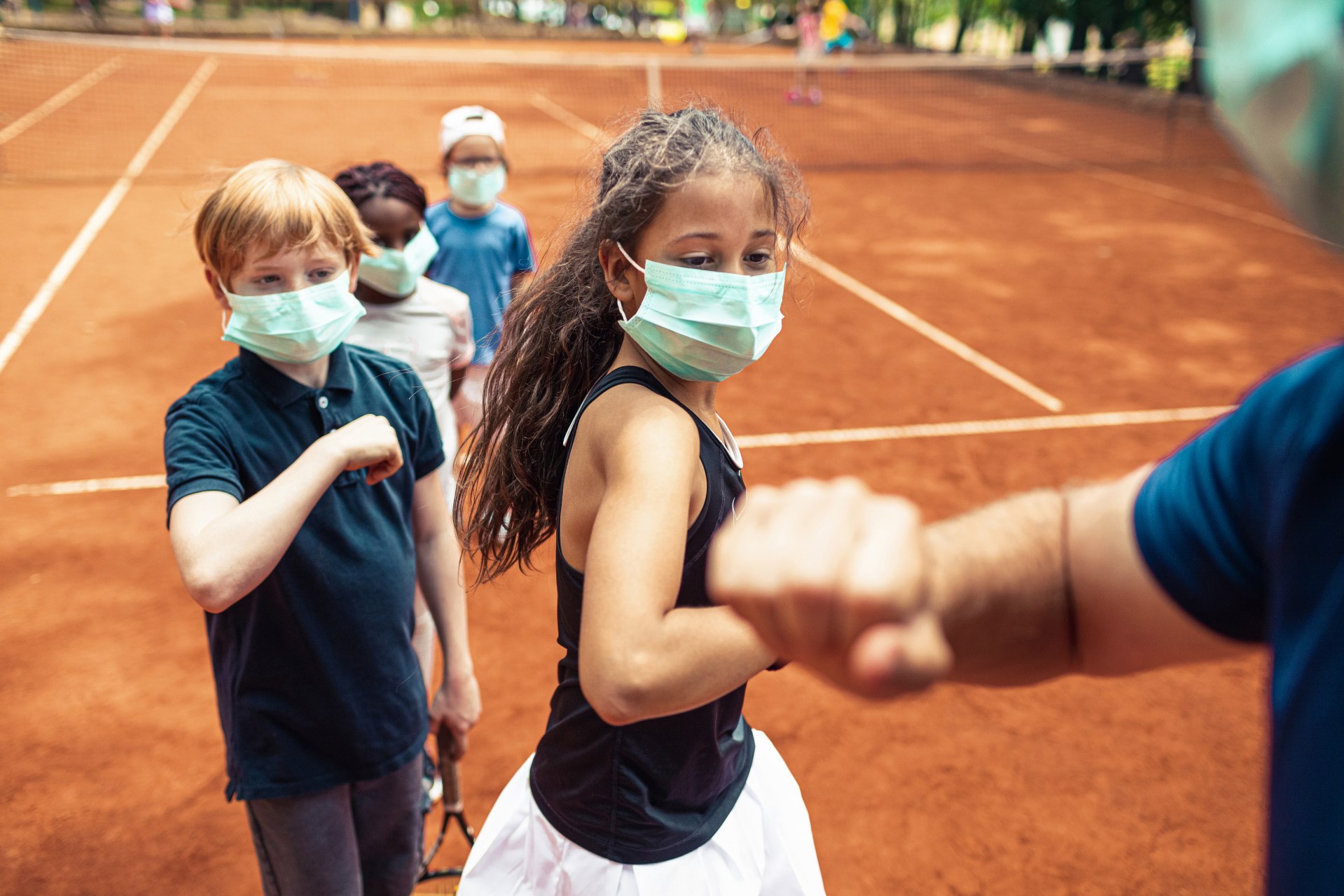 Ragazzi su un campo da tennis con la mascherina