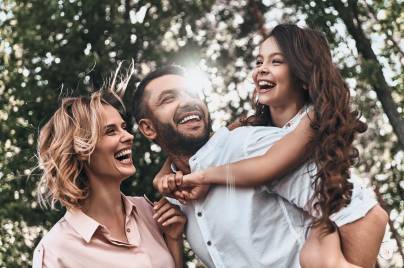famiglia composta da madre padre e figlia che giocano tra gli alberi