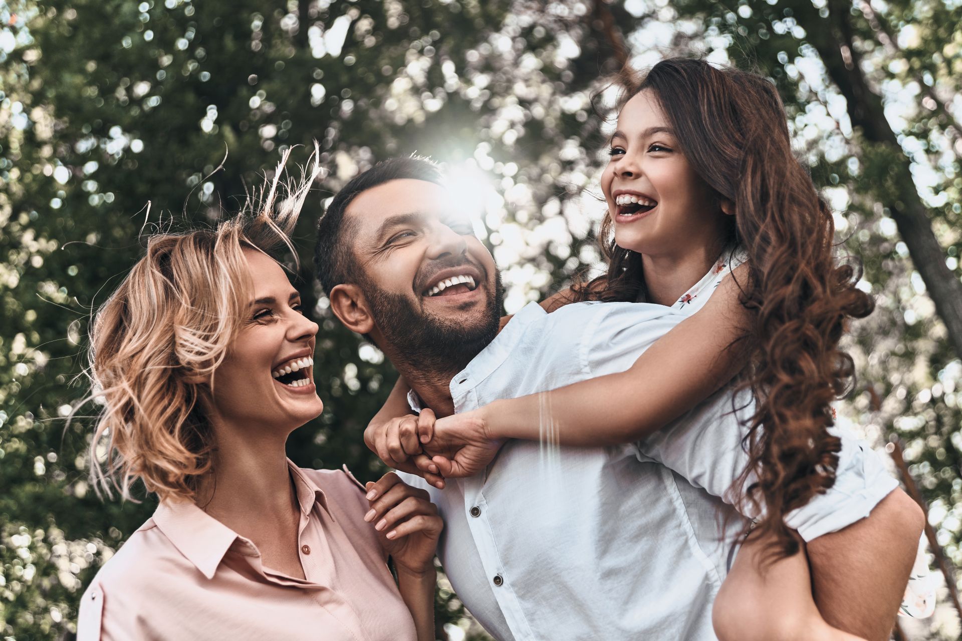 famiglia composta da madre padre e figlia che giocano tra gli alberi