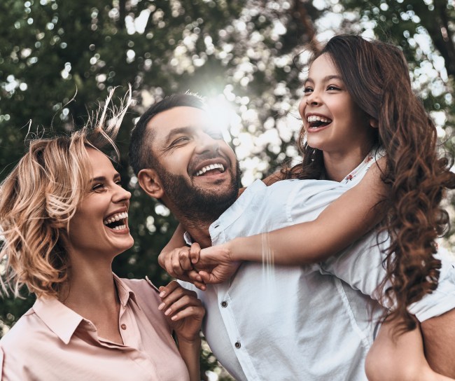famiglia composta da madre padre e figlia che giocano tra gli alberi