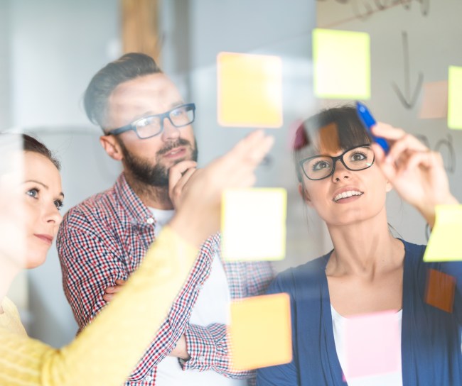 Persone che guardano post it su una lavagna