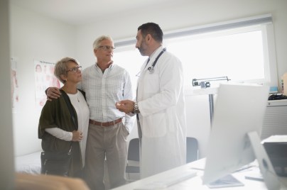 Coppia in visita dal medico che si abbraccia